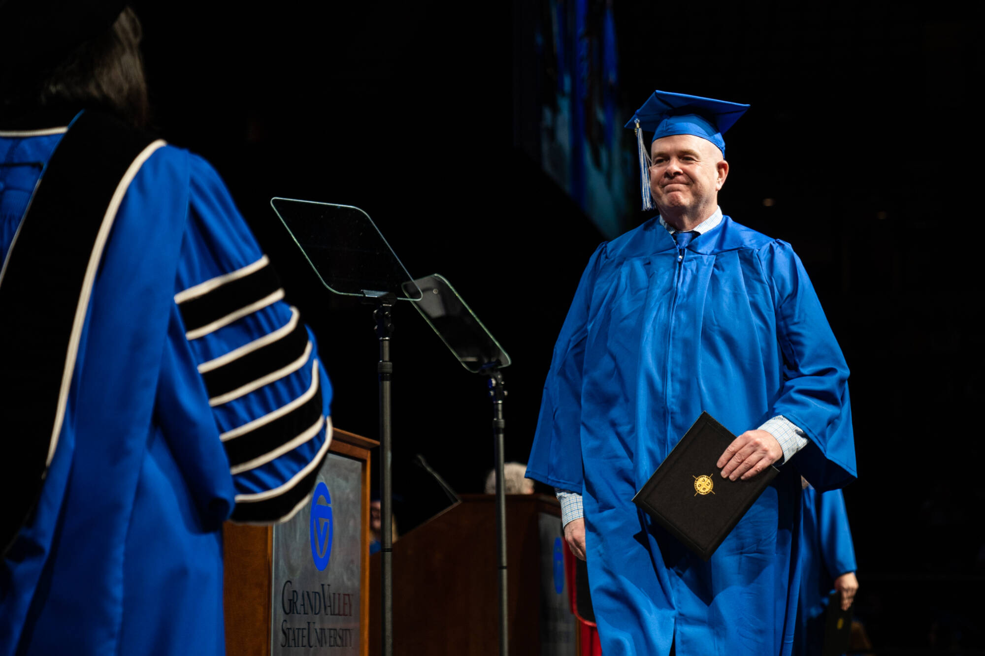 adult student walking across the stage during graduation